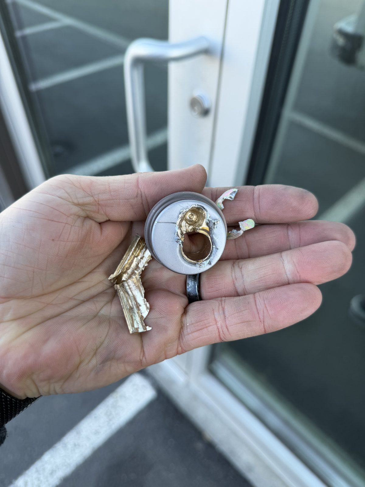 Close-up of destroyed mortise cylinder with shattered brass pieces from incorrect drilling